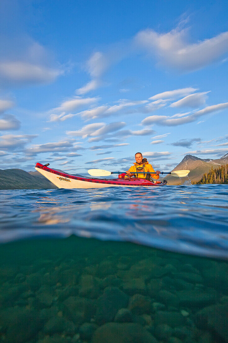 'Kayaker on Kusawa Lake at sunset, shot half above and half below water; Yukon, Canada'