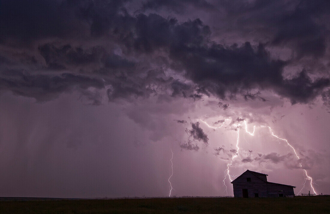 'Lightning strikes over the prairies as it approaches an old abandoned farm house; Val Marie, Saskatchewan, Canada'