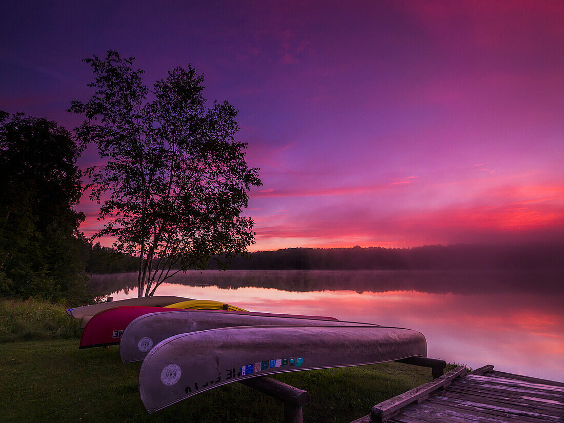 'Sunrise explodes over Echo Lake in Aroostook State Park with canoes on the shore; Presque Isle, Maine, United States of America'