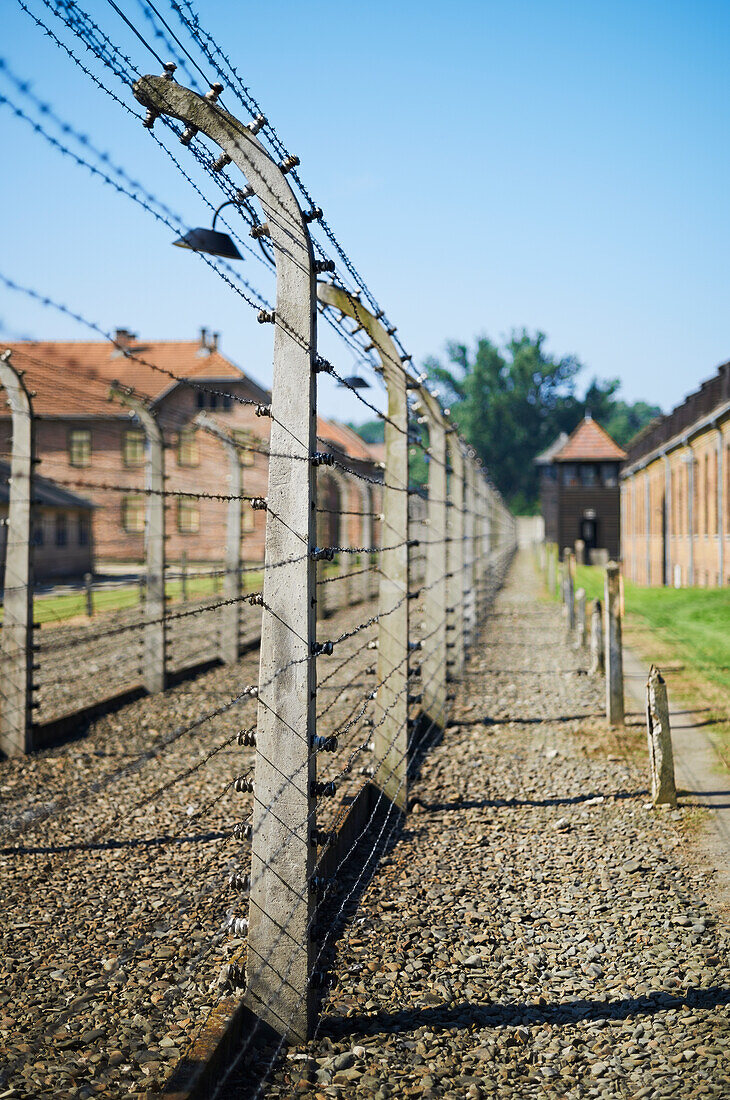 'Barbed wire fences with cell blocks and guard tower in Auschwitz concentration camp; Osweciem, Poland'