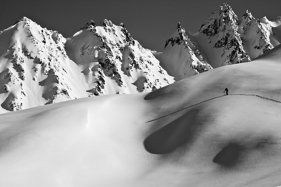 Backcountry skier skinning in the Iguana Backs of the Chugach Range above Valdez, Southcentral Alaska