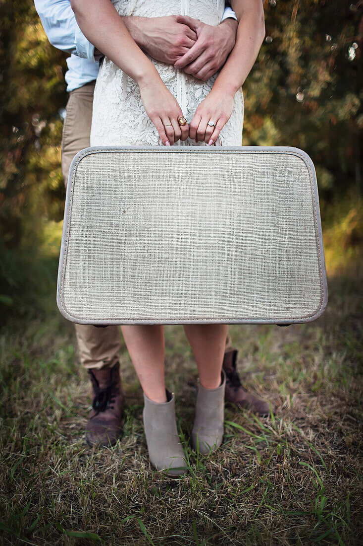 'A couple holding a vintage suitcase; Edmonton, Alberta, Canada'