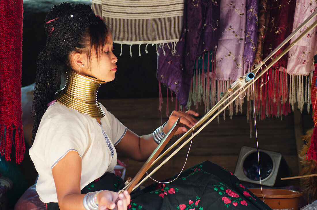 'Woman from the long neck Karenni hill tribe tribe weaving fabric; Thaton, Chiang Rai, Thailand'