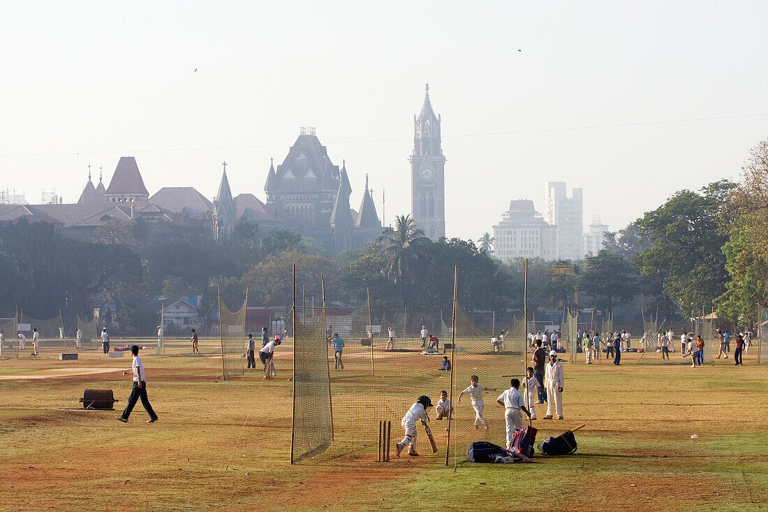 'Early morning games of cricket and in the nets at Cross Maiden with Law Courts in background; Mumbai, Maharashtra State, India'