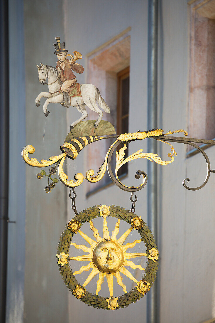 'Close up of gold sign with a sun, horn, and person on a horse; Rattenberg, Austria'