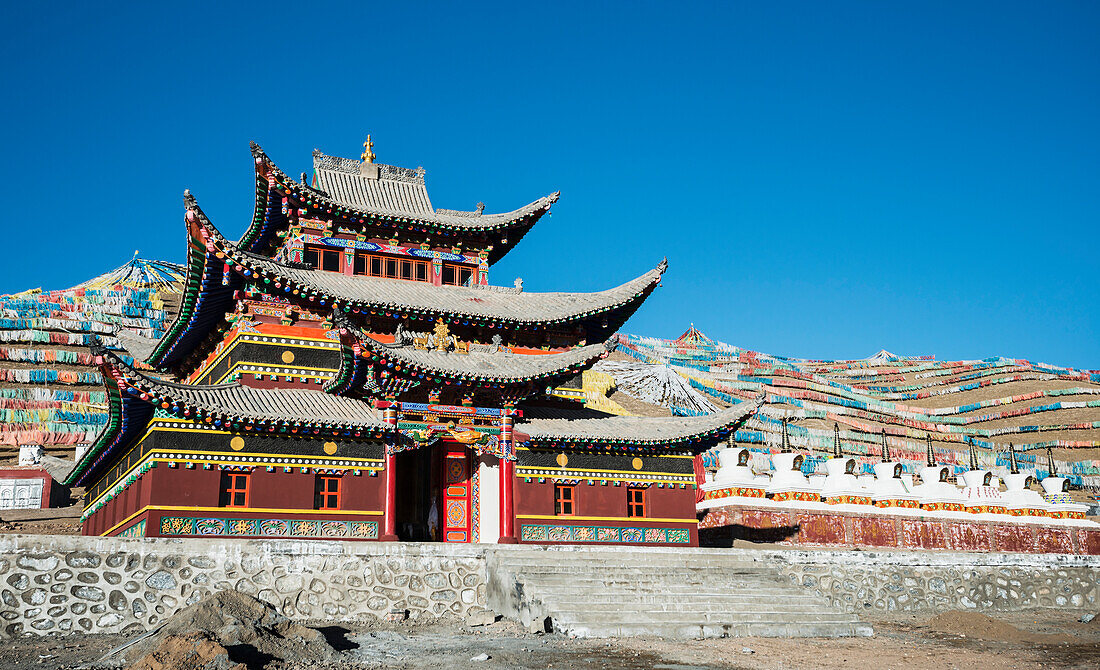 'Colourful Buddhist temple and many prayer flags and stupas at a Tibetan monastery near Hot Spring city; Madoi County, Tibet'
