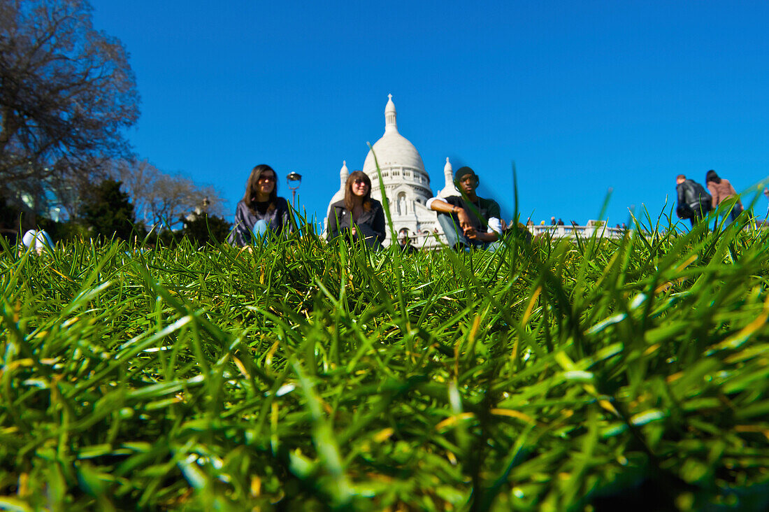 'Sitting on the grass with a view of a building's white dome roof in the background; Paris, France'