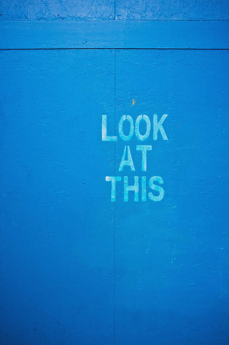 'Words on a blue wall saying look at this; London, England'