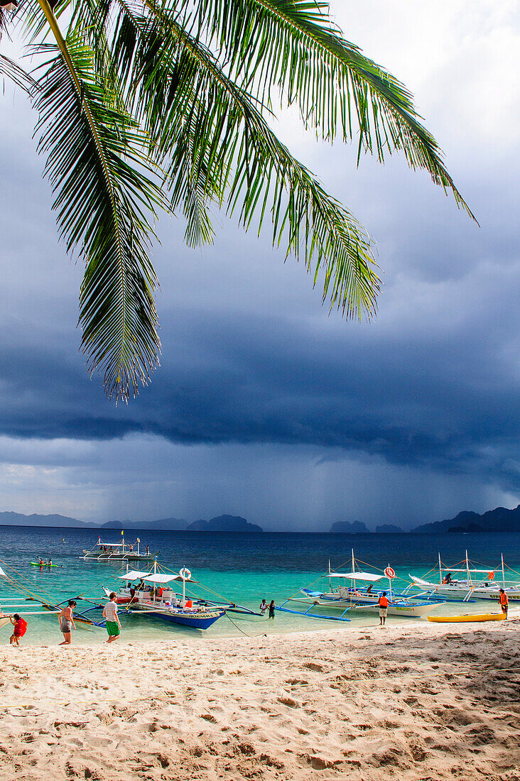 Outrigger boats before a strom anchoring on a sandy beach  in  the Bacuit archipelago, Palawan, Philippines, Southeast Asia, Asia