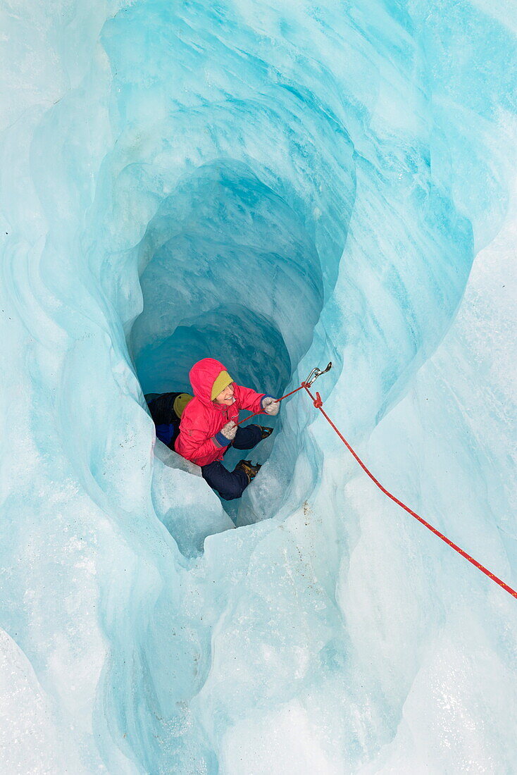 Rock climber moving up ice cave, Fox Glacier, South Island, New Zealand, Pacific