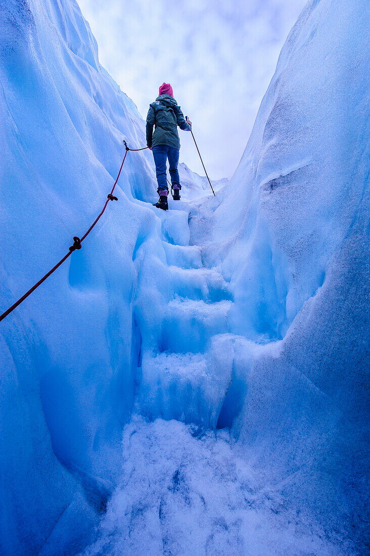 Woman walking steps out of a ice cave in Fox Glacier, Westland Tai Poutini National Park, South Island, New Zealand, Pacific