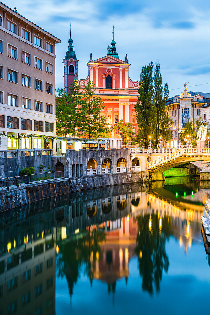 Ljubljana triple bridge (Tromostovje) and Franciscan Church of the Annunciation reflected in Ljubljanica River at night, Ljubljana, Slovenia, Europe