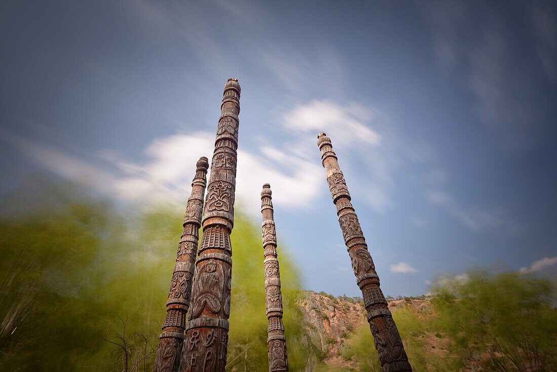 Naxi poles with wood carvings with moving clouds in a long exposure, Lijiang, Yunnan, China, Asia