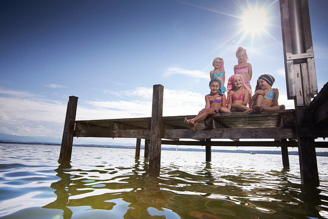 Girls sitting on a jetty, hairs wrapped in towels, lake Starnberg, Upper Bavaria, Bavaria, Germany