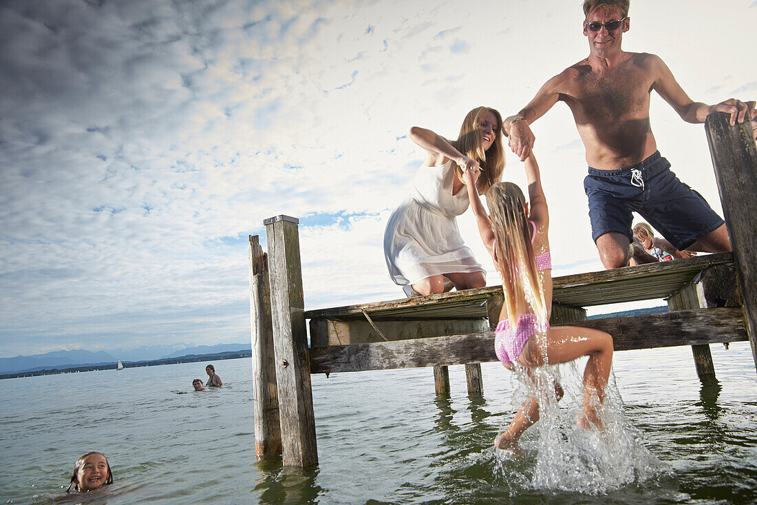 Parents lifting daughter up, lake Starnberg, Upper Bavaria, Bavaria, Germany