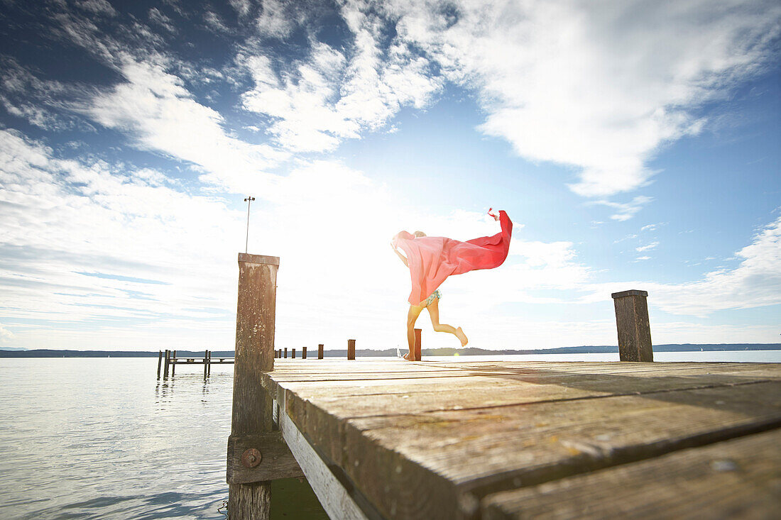 Girl running along a jetty, lake Starnberg, Upper Bavaria, Bavaria, Germany