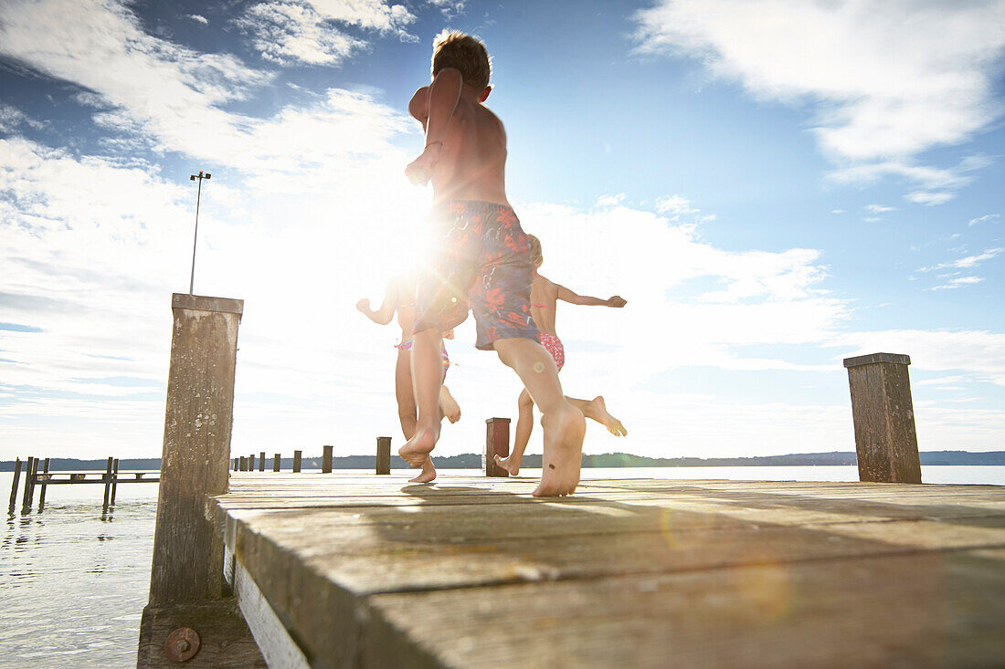 Children running along a jetty, lake Starnberg, Upper Bavaria, Bavaria, Germany