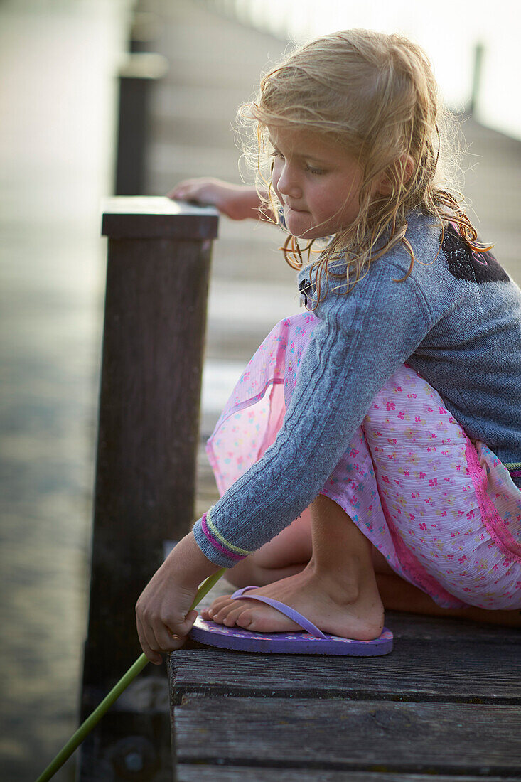 Mädchen kniet auf einem Steg, Starnberger See, Oberbayern, Bayern, Deutschland