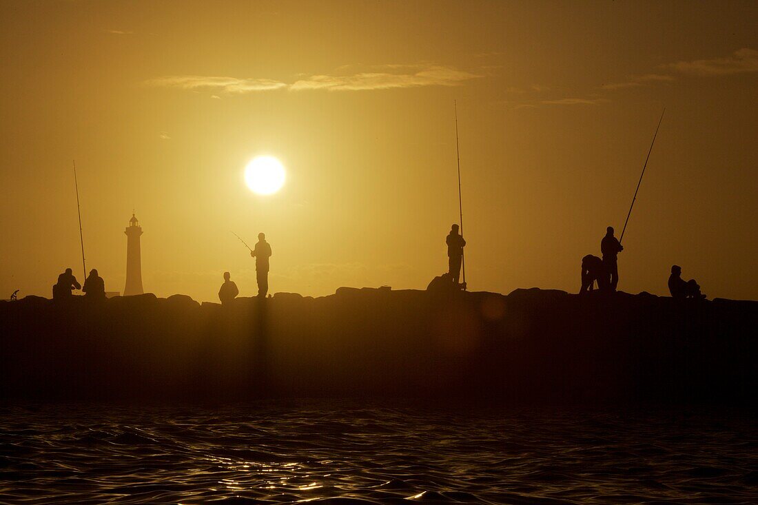 Fishermen on a pier in Rabat at sunset, Morocco