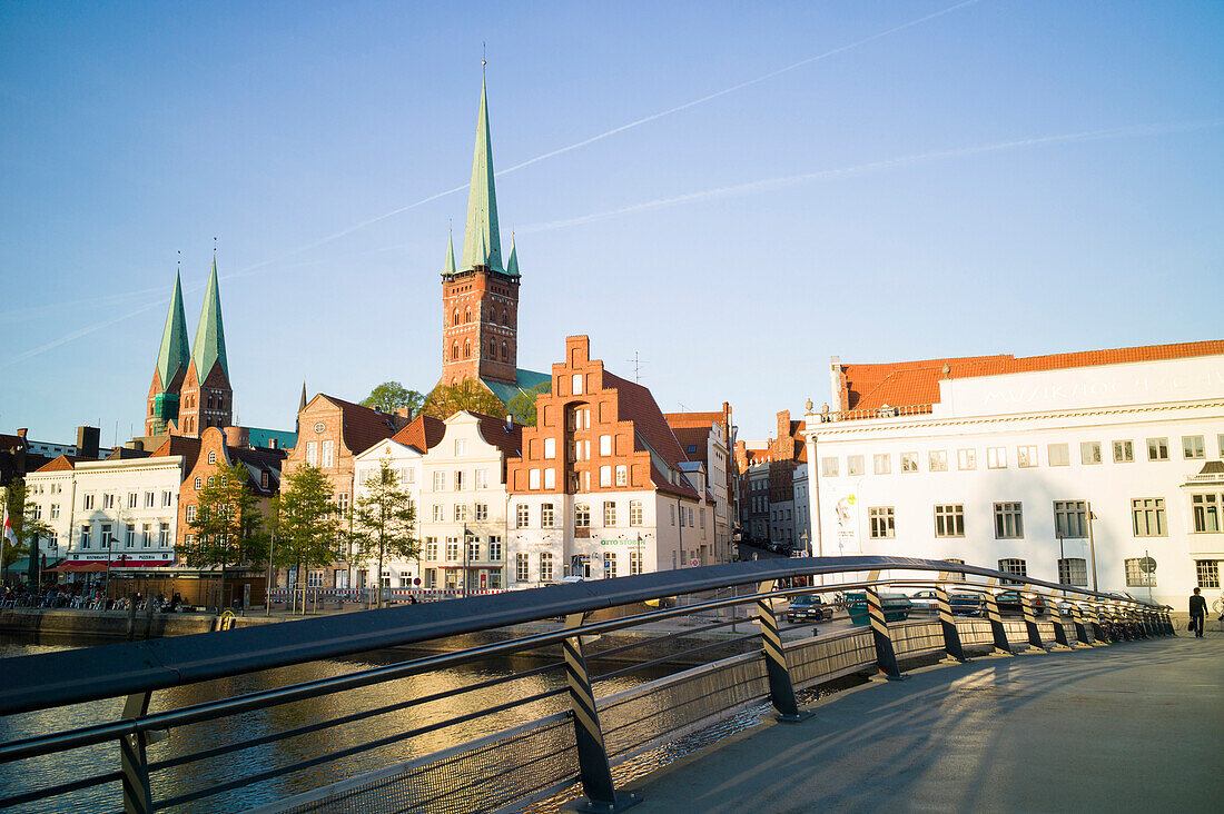 Pedestrian bridge crossing river Trave, conservatory and churches of St. Peter and St. Mary in background, historic city, Lubeck, Schleswig-Holstein, Germany