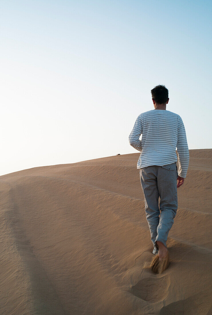 Mann auf einer Düne in der Wüste, Dubai, Vereinigte Arabische Emiraten