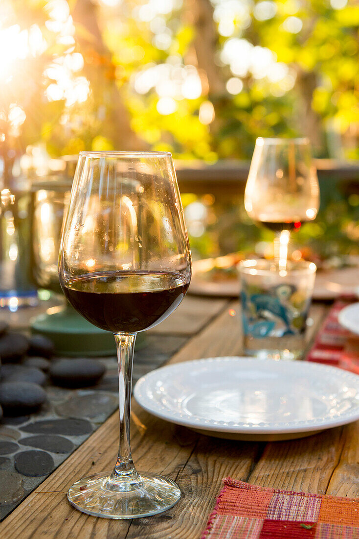 'Glasses of red wine on a table set for a meal; Ontario, Canada'