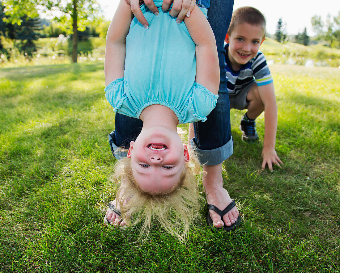 'Mother hanging her daughter upside down in a park; Edmonton, Alberta, Canada'