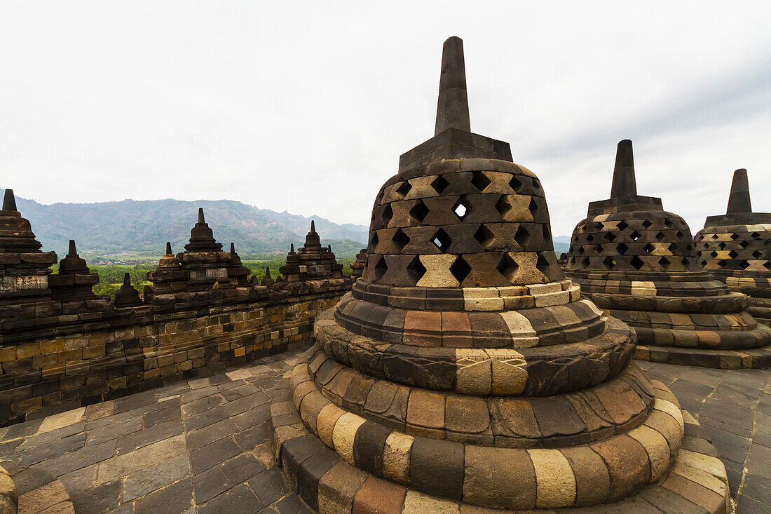 Latticed stone stupas containing Buddha statues on the upper terrace, Borobudur Temple Compounds, Central Java, Indonesia
