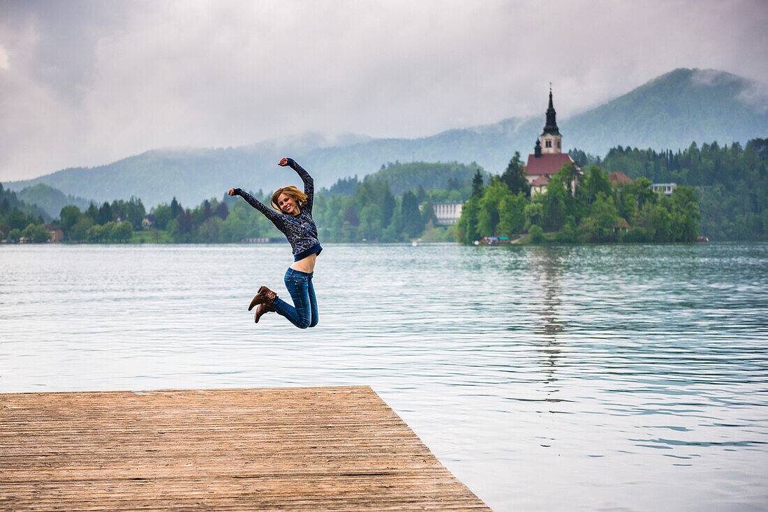 Woman jumping for joy, Lake Bled, Julian Alps, Gorenjska, Slovenia, Europe