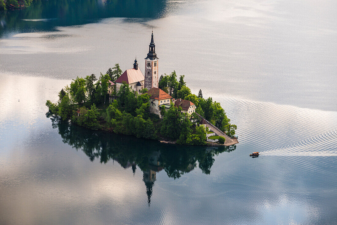 Lake Bled boat (Pletna) approaching Lake Bled Island at sunrise, Gorenjska, Slovenia, Europe