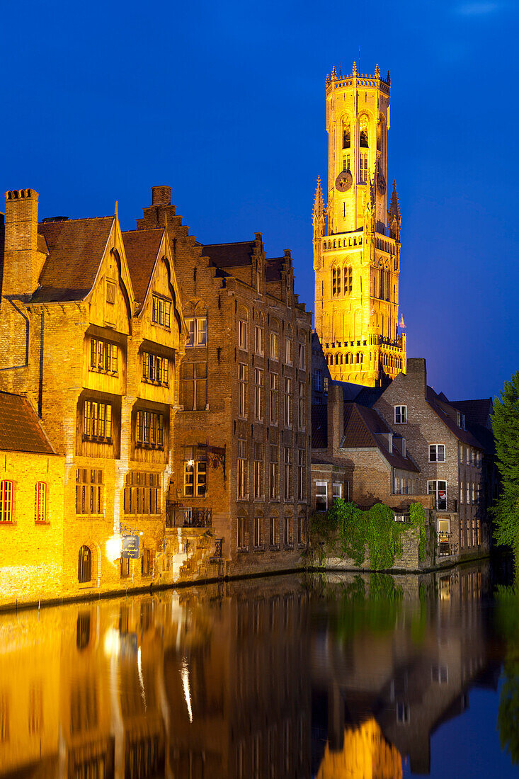 The Belfry and buildings lit up at night along a Canal in the Historic Center of Bruges, UNESCO World Heritage Site, Belgium, Europe
