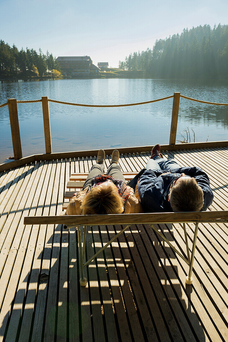 Couple sunbathing at Lake Mummelsee, Seebach, near Achern, Black Forest, Baden-Wuerttemberg, Germany