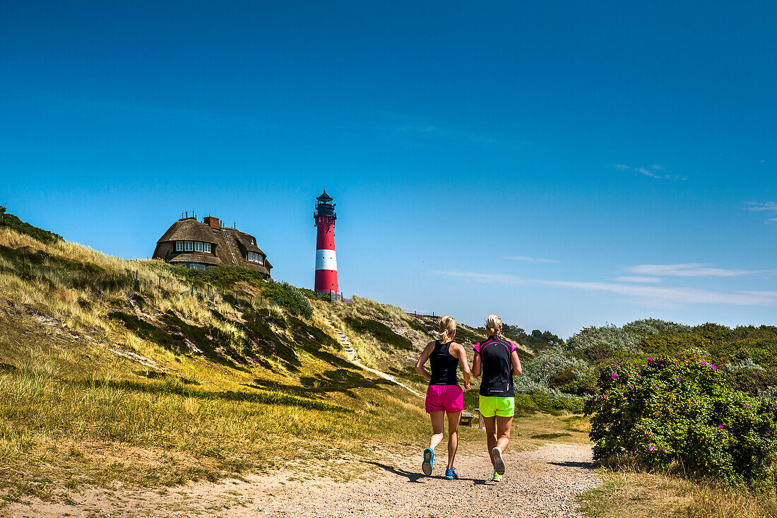 Jogger in front of lighthouse, Hoernum, Sylt Island, North Frisian Islands, Schleswig-Holstein, Germany