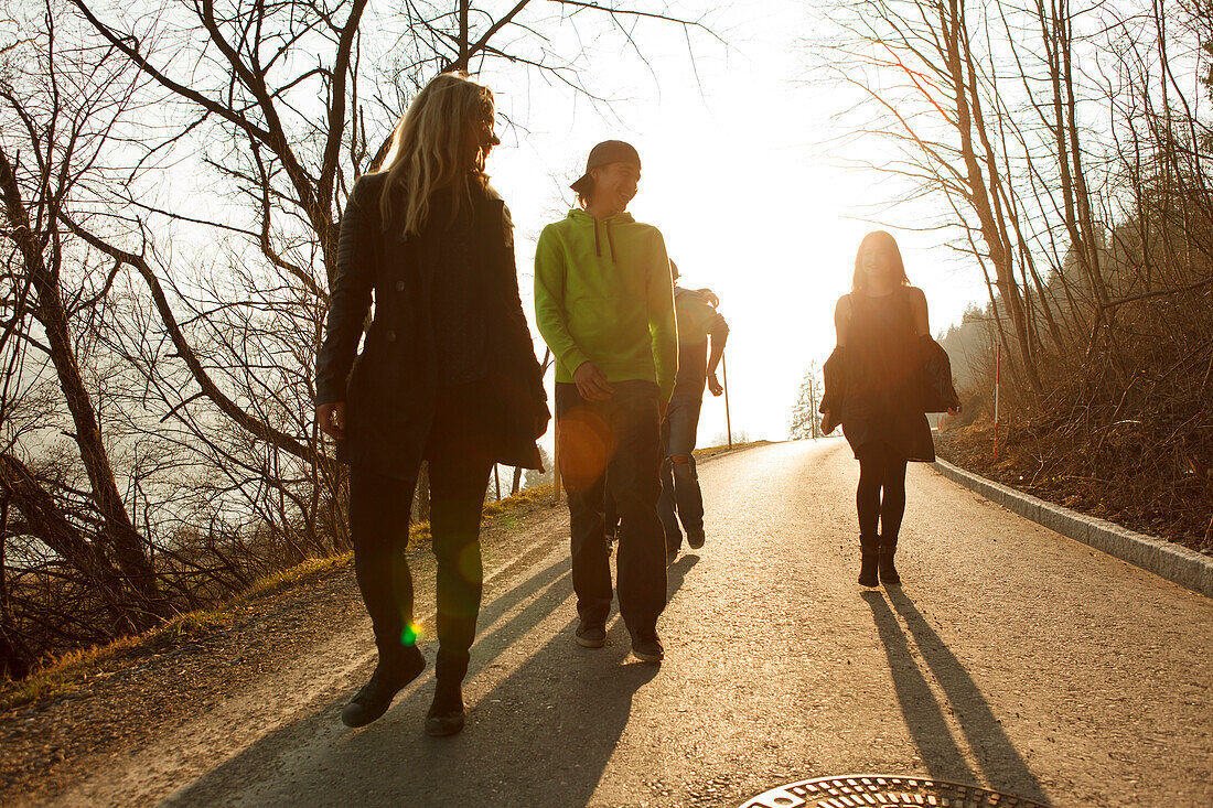 Gruppe junger Leute laufen eine Landstraße entlang, Großer Alpsee, Immenstadt im Allgäu, Bayern, Deutschland