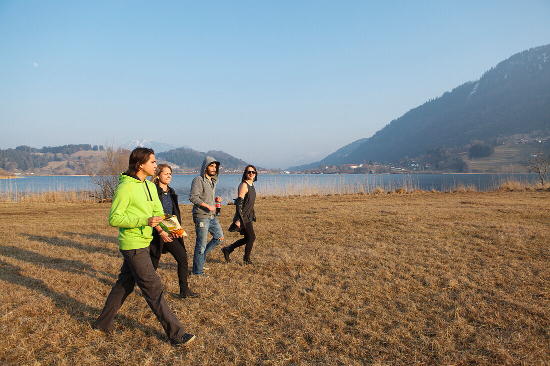 Young people crossing a meadow, Grosser Alpsee, Immenstadt, Bavaria, Germany