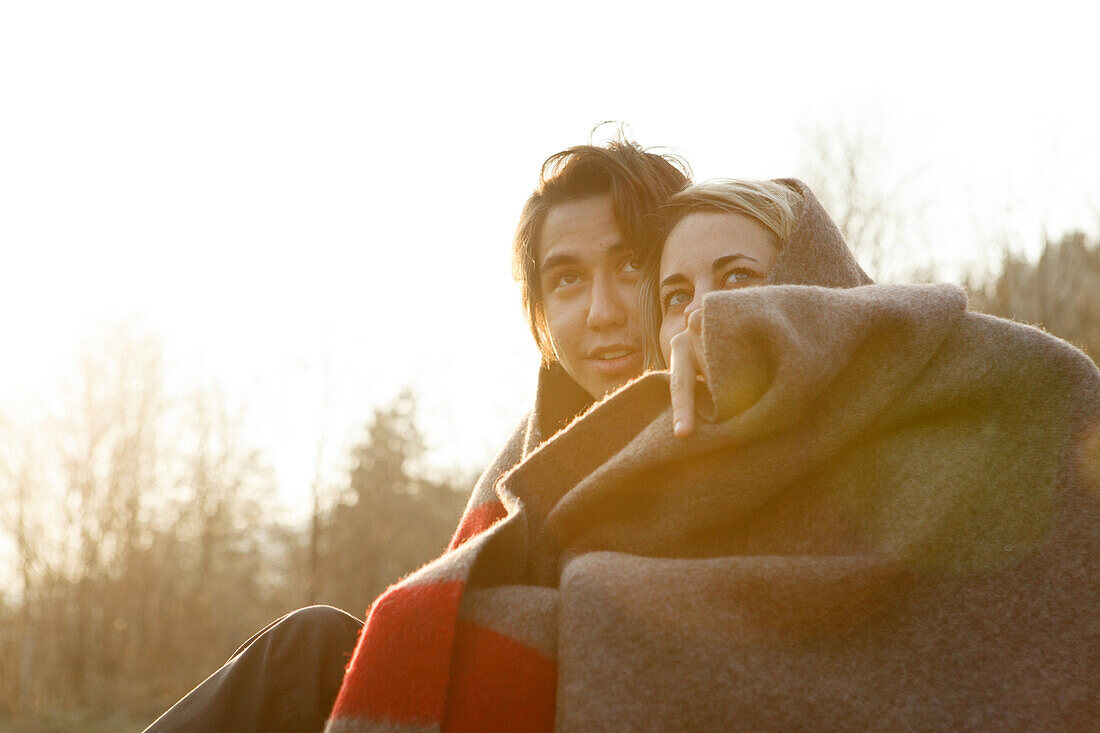 Young couple wrapped in a blanket, Grosser Alpsee, Immenstadt, Bavaria, Germany