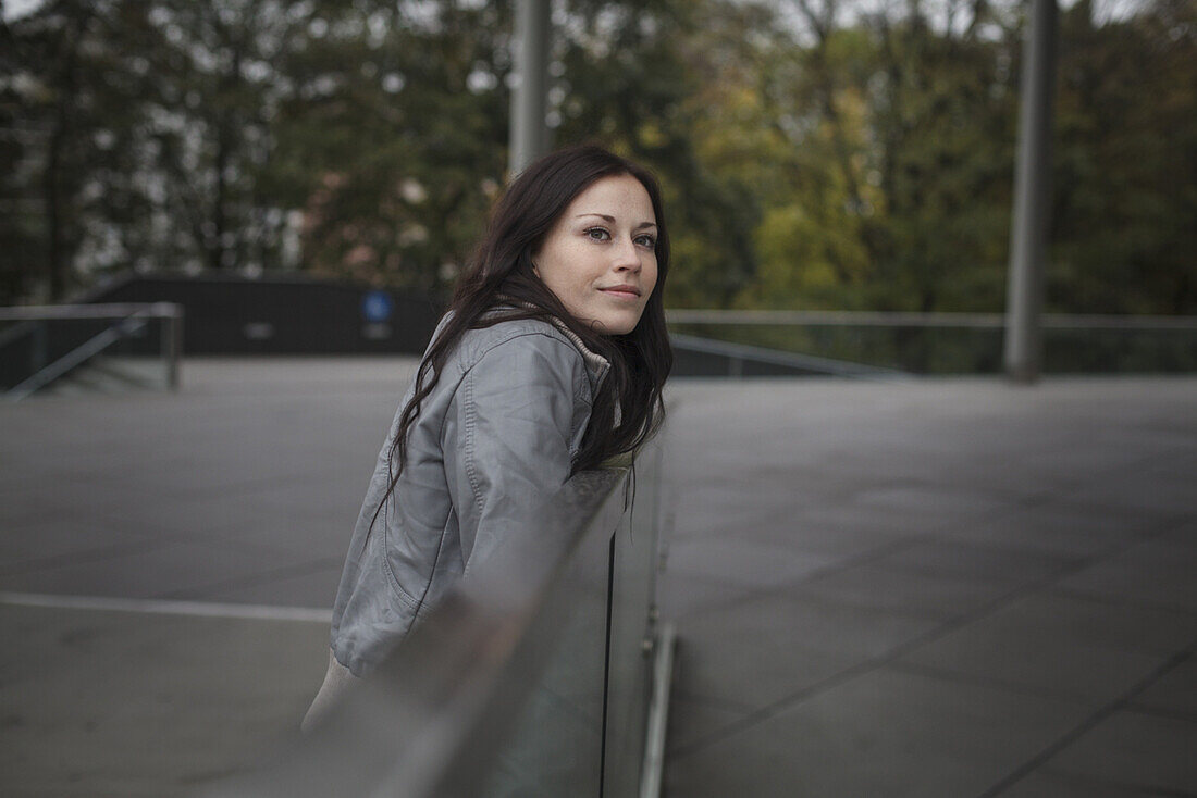 Young woman leaning against a balustrade, Munich, Bavaria, Germany