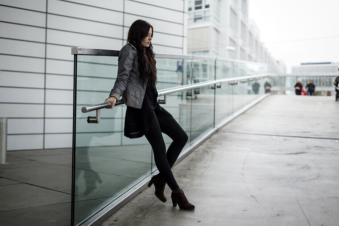 Young woman leaning against a balustrade, Munich, Bavaria, Germany