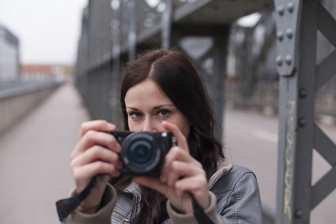 Young woman taking photos on Hacker Bridge, Munich, Bavaria, Germany