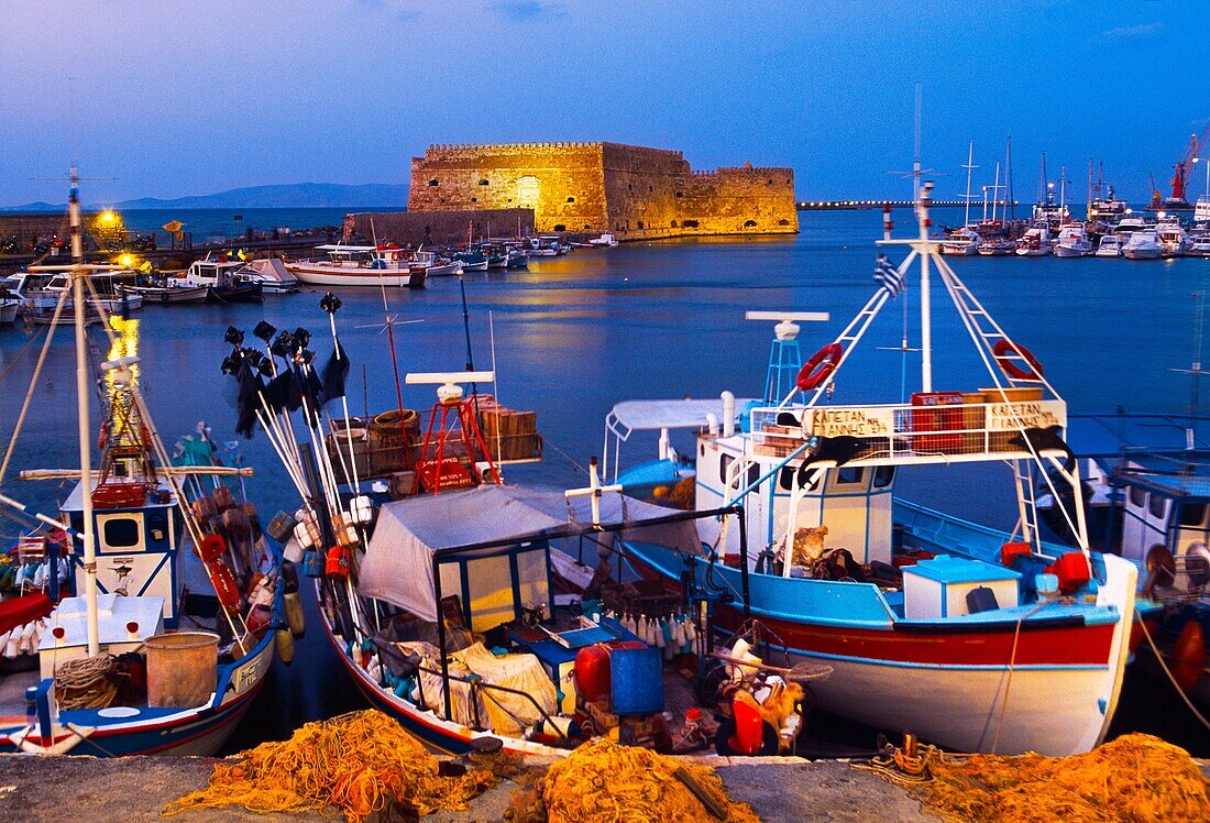 Cretan boat moored Heraklion harbour and Venetian fortress Koules Castle, Iraklio, Crete, Greece.