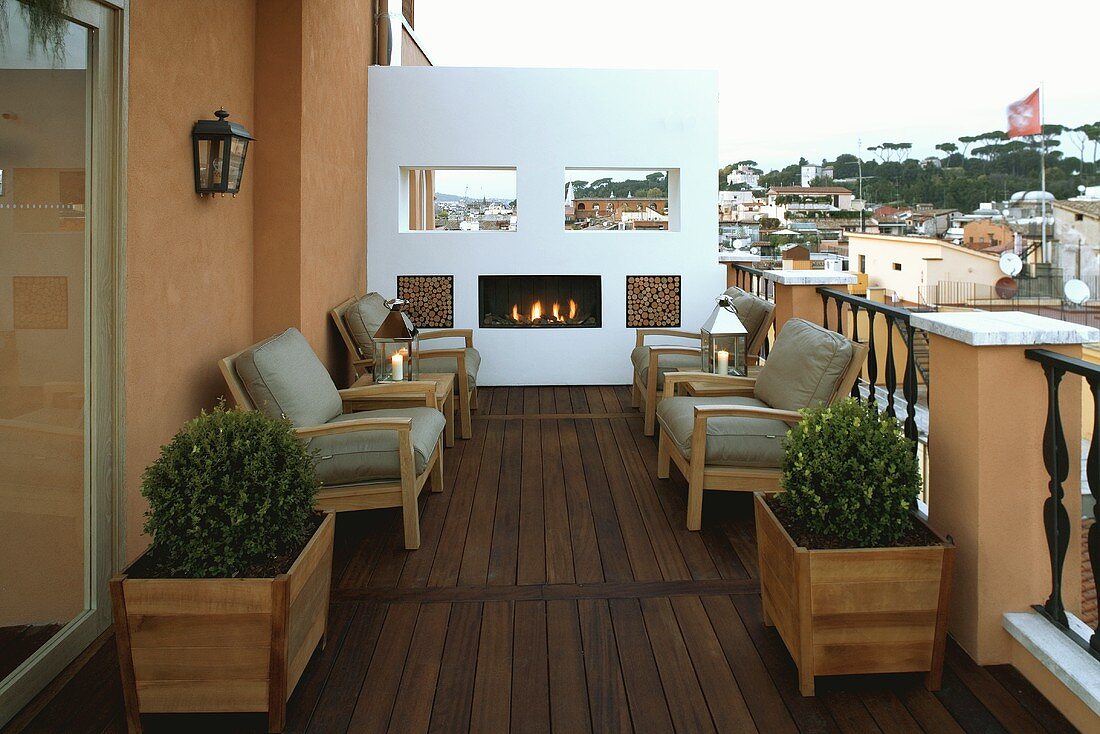 Crackling fire in a fireplace on a roof terrace with wood floor and seating with gray upholstery
