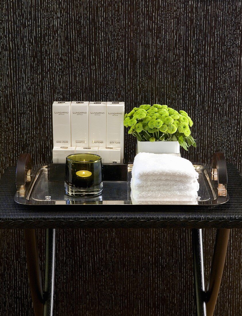 Side table with spa products in front of a wall with wood paneling stained black