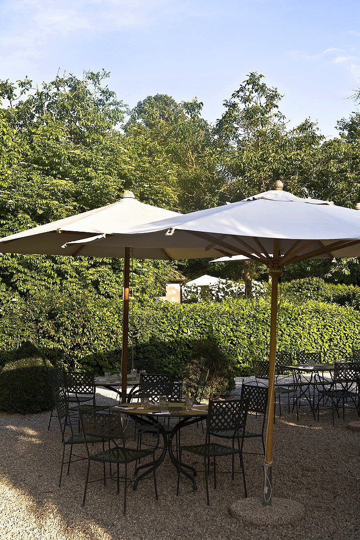 Sunny day -- garden chairs and table with a sun umbrella on a gravel patio