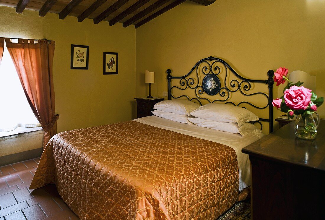 Bedroom under a roof -- double bed with a metal headboard and elegant bedspread