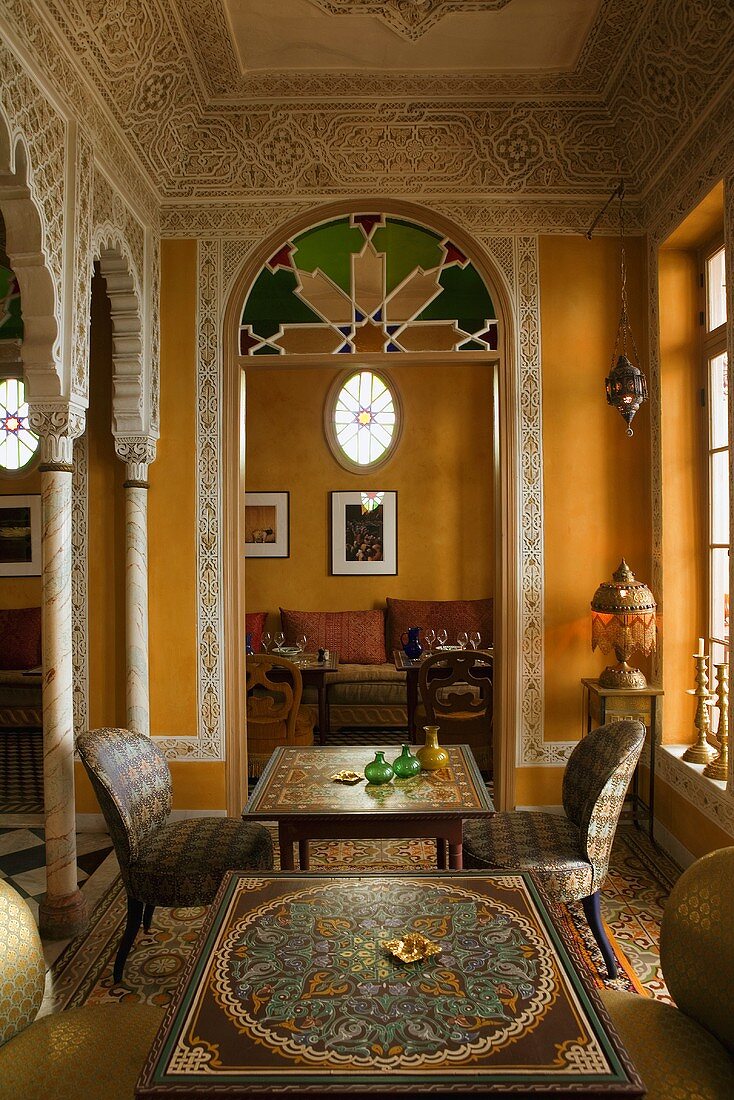 Elegant Moroccan salon with wall frescos and a view through an archway of a sofa