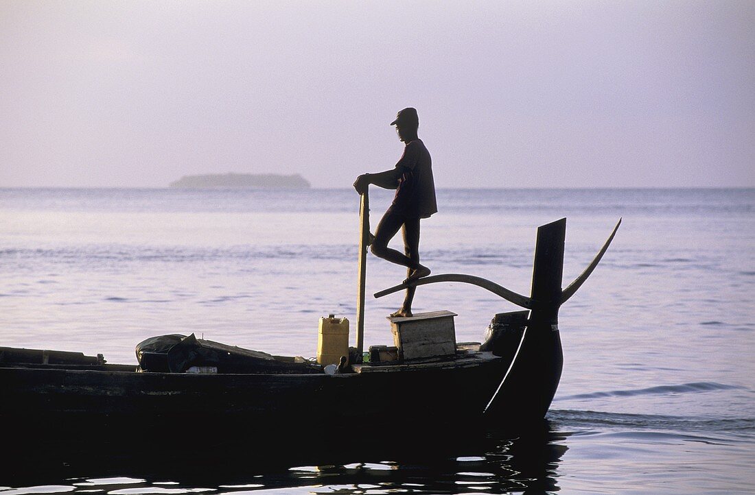 Sunrise with a fishing boat on the sea -- a fisherman serenely steers a full boat