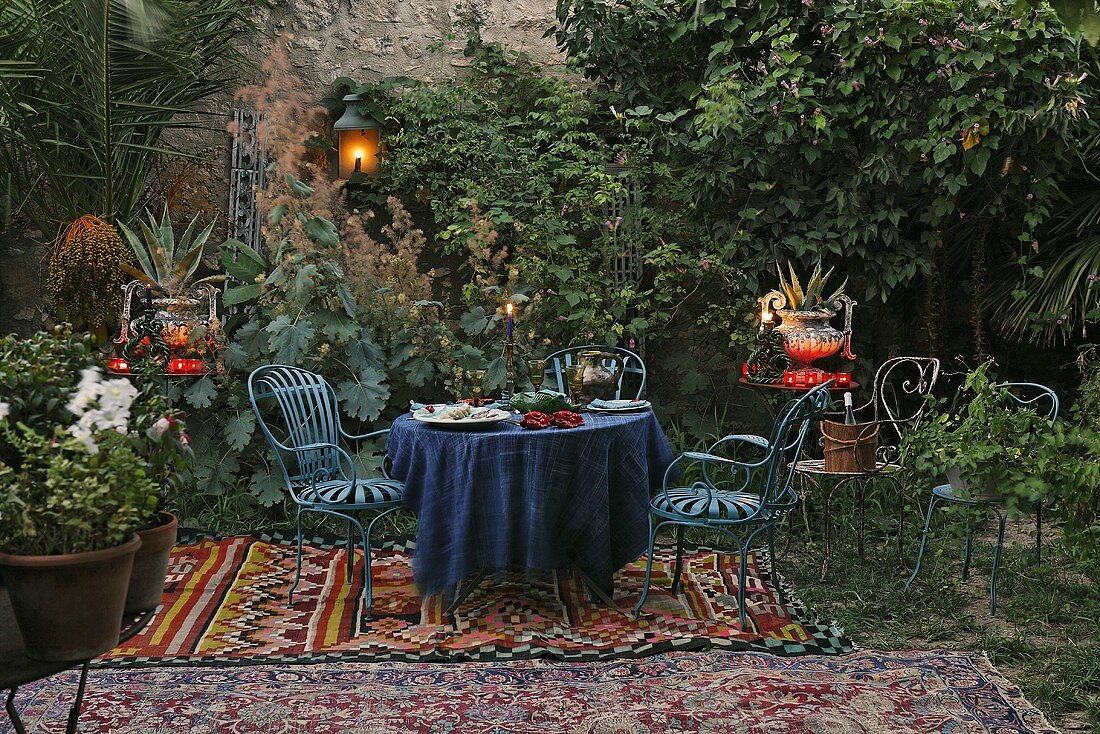 Romantic picnic -- blue patio furniture on a oriental rug with lanterns and tea lights