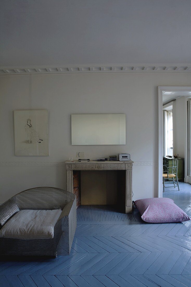 Grey armchair on a gray lacquer floor with a herringbone pattern and fireplace in a country style living room