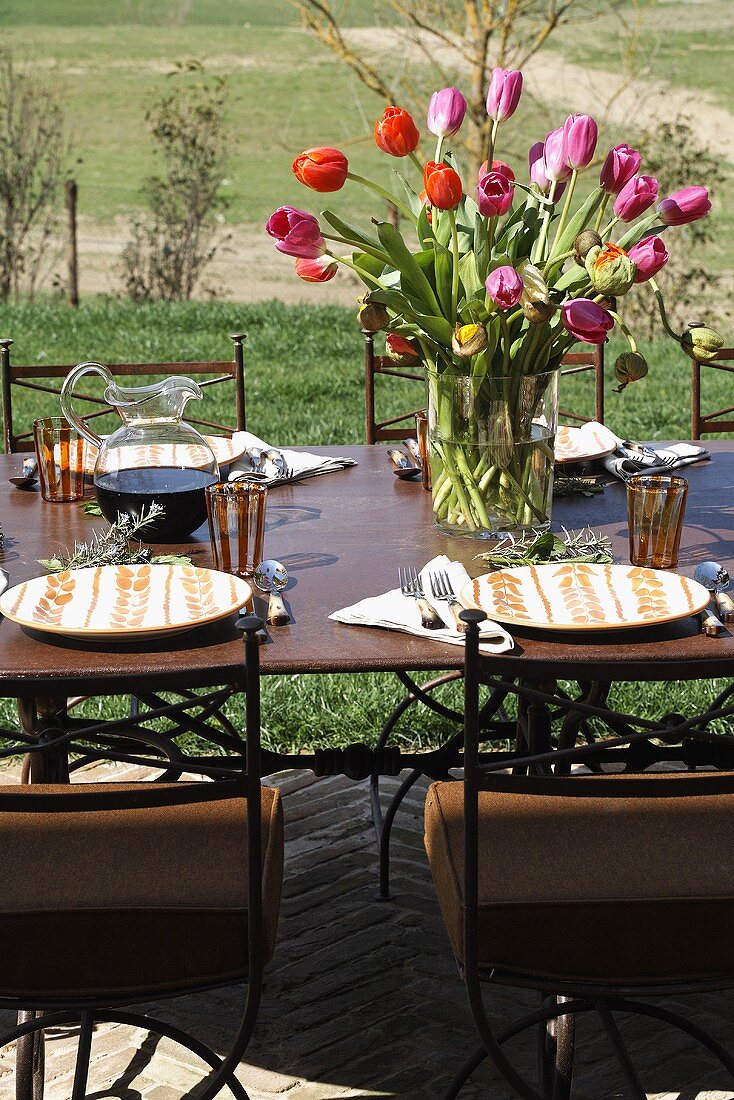 Bunter Tulpenstrauss auf gedecktem Tisch im Freien