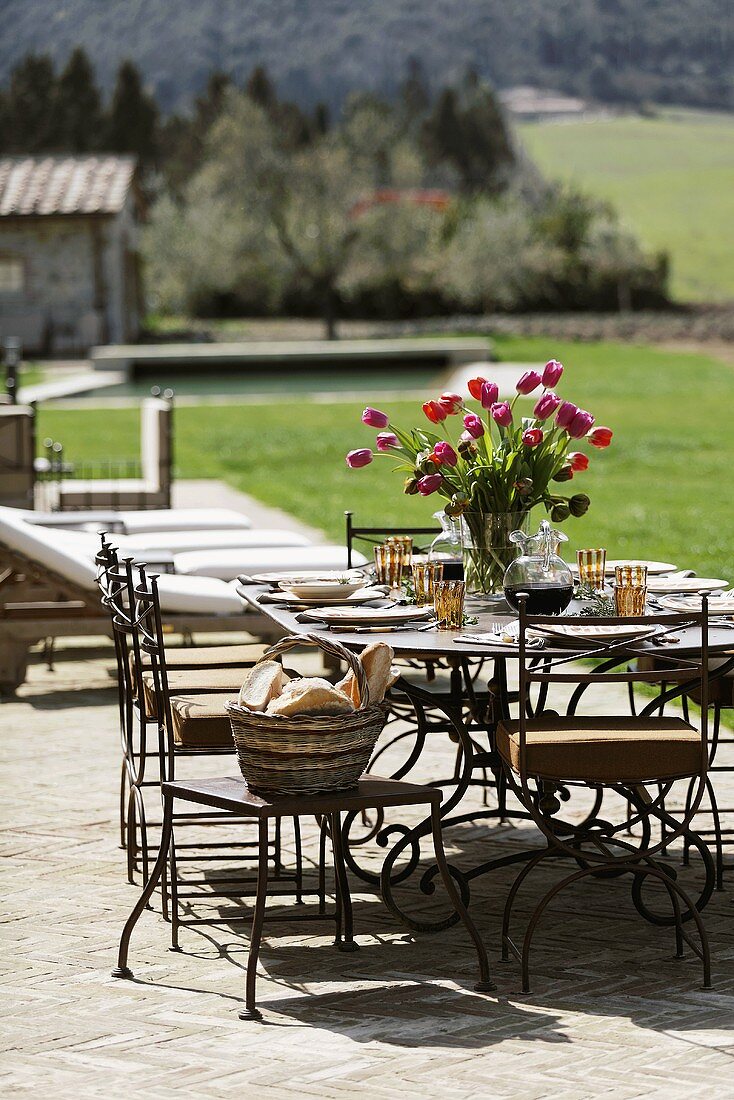 A table laid on a terrace with a colourful bunch of flowers